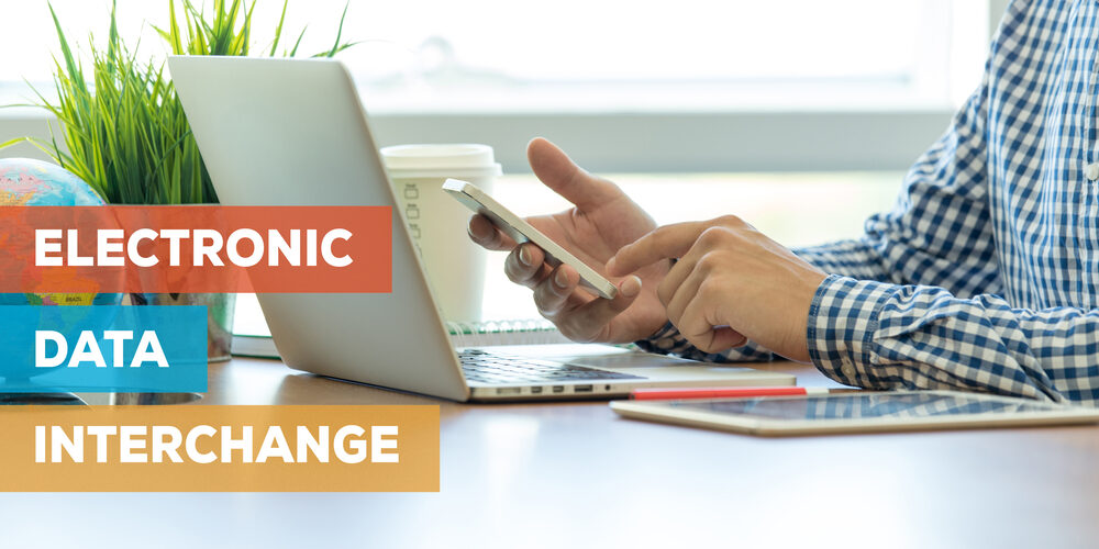 man-at-laptop-with-electronic-data-interchange-text Man on laptop and phone with text reading electronic data interchange