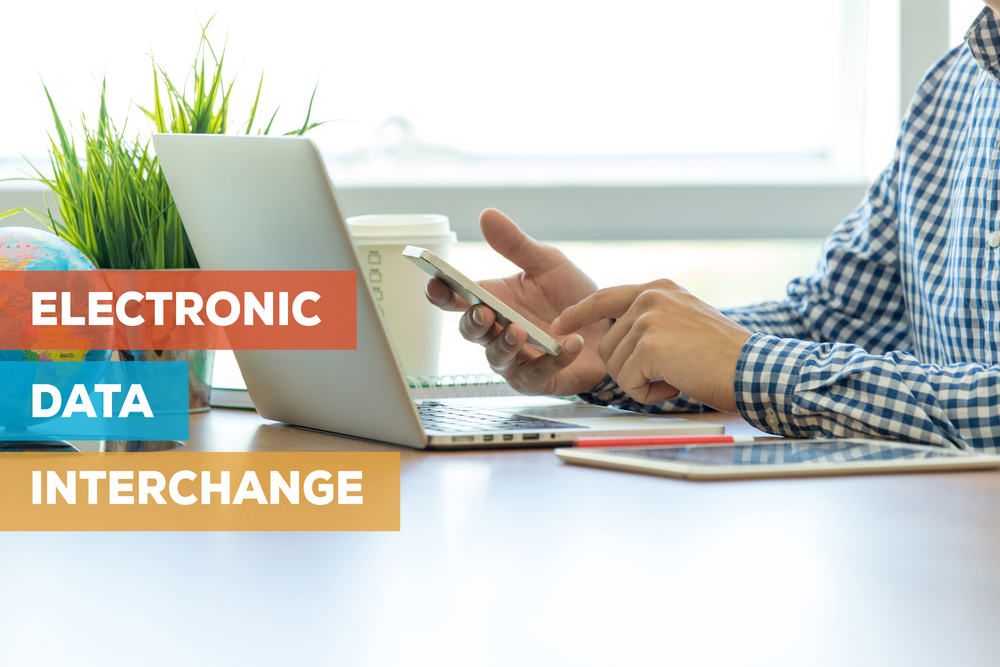 man-at-laptop-with-electronic-data-interchange-text Man on laptop and phone with text reading electronic data interchange