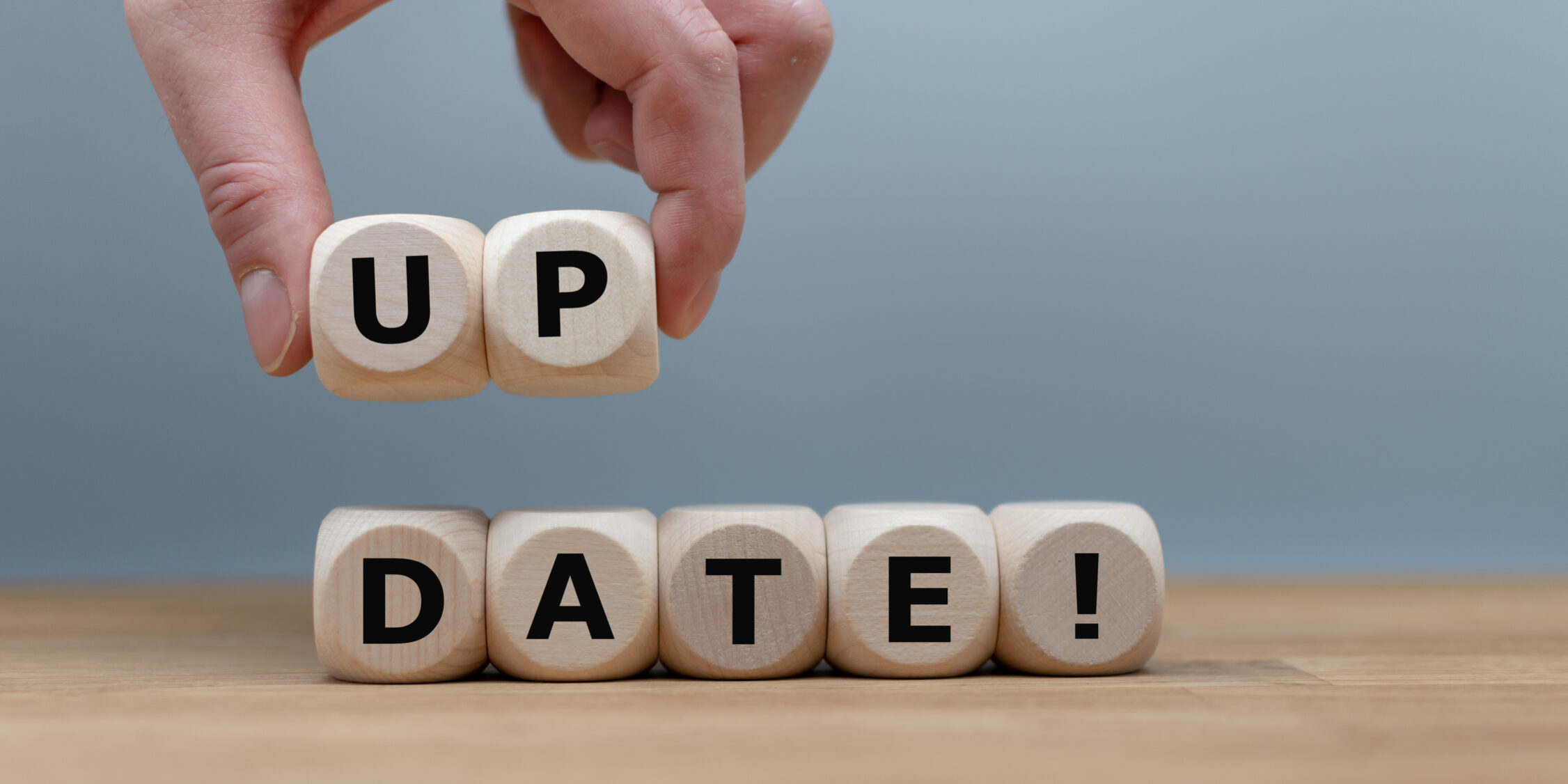Dice form the word “UPDATE!” while a hand rises the letters “UP”.