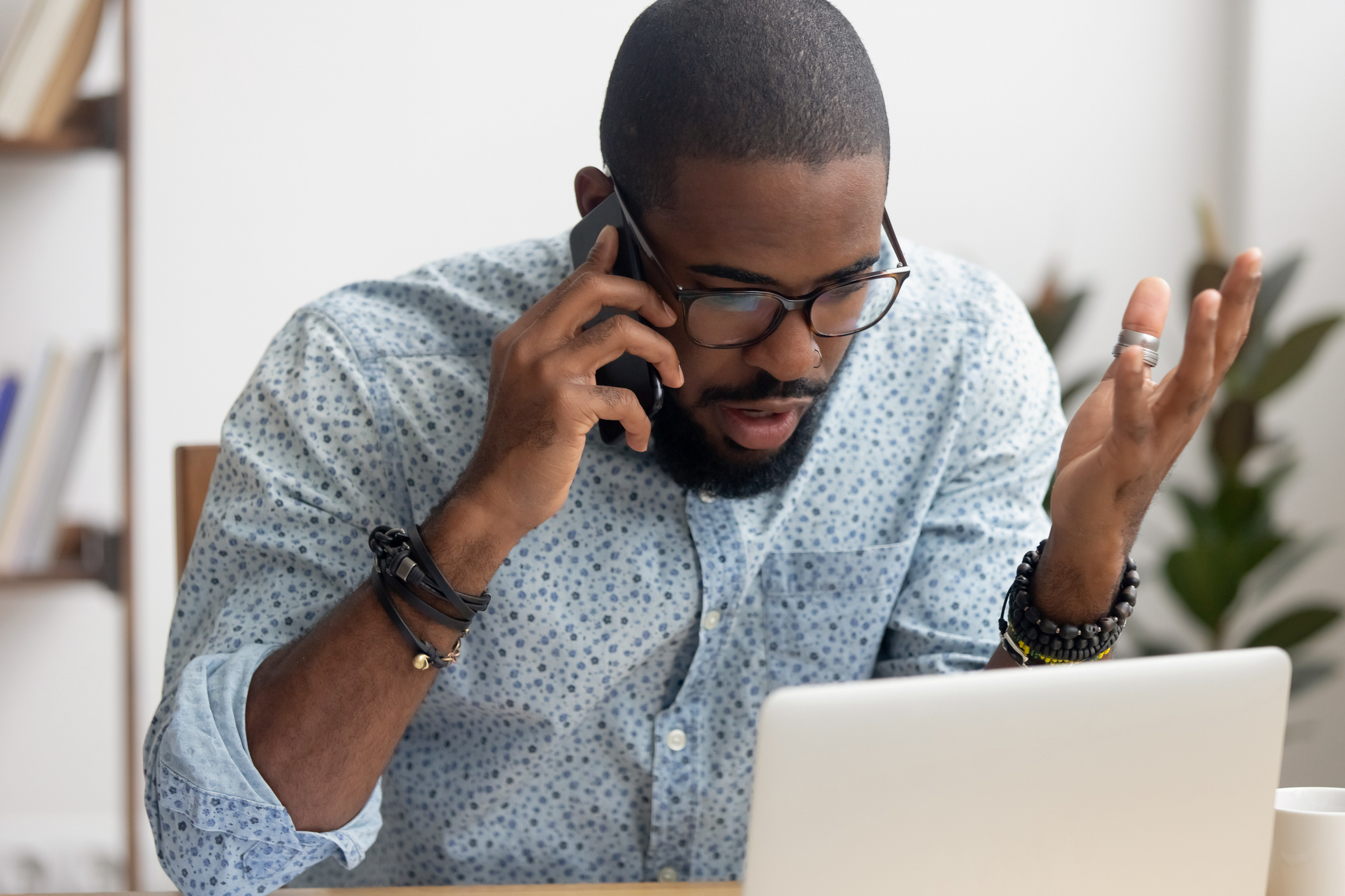 Angry mad african-american businessman talking on cellphone in office