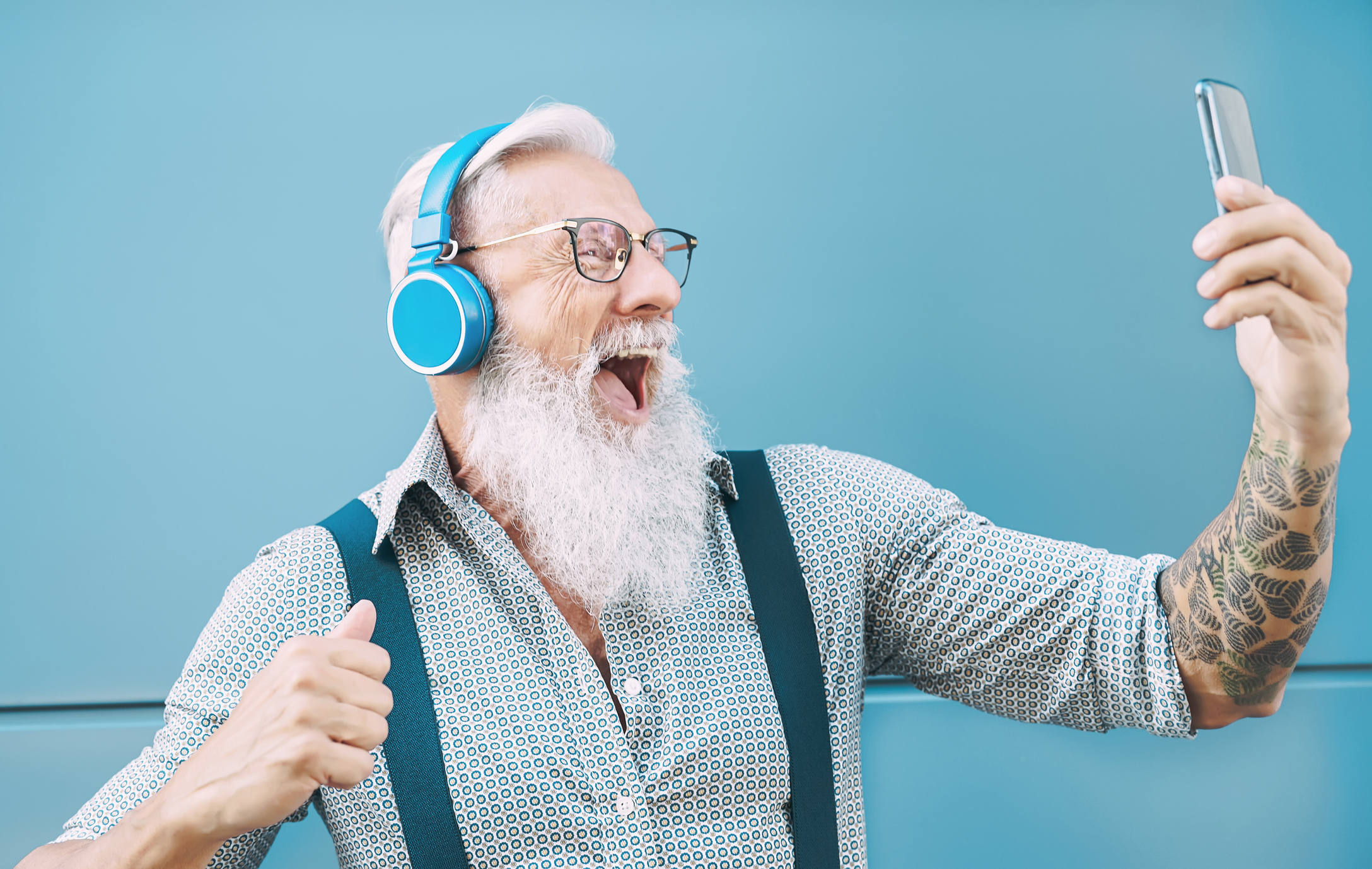 Happy senior man taking selfie while listening music with headphones – Hipster mature male having fun using mobile smartphone playlist apps – technology and elderly lifestyle people concept