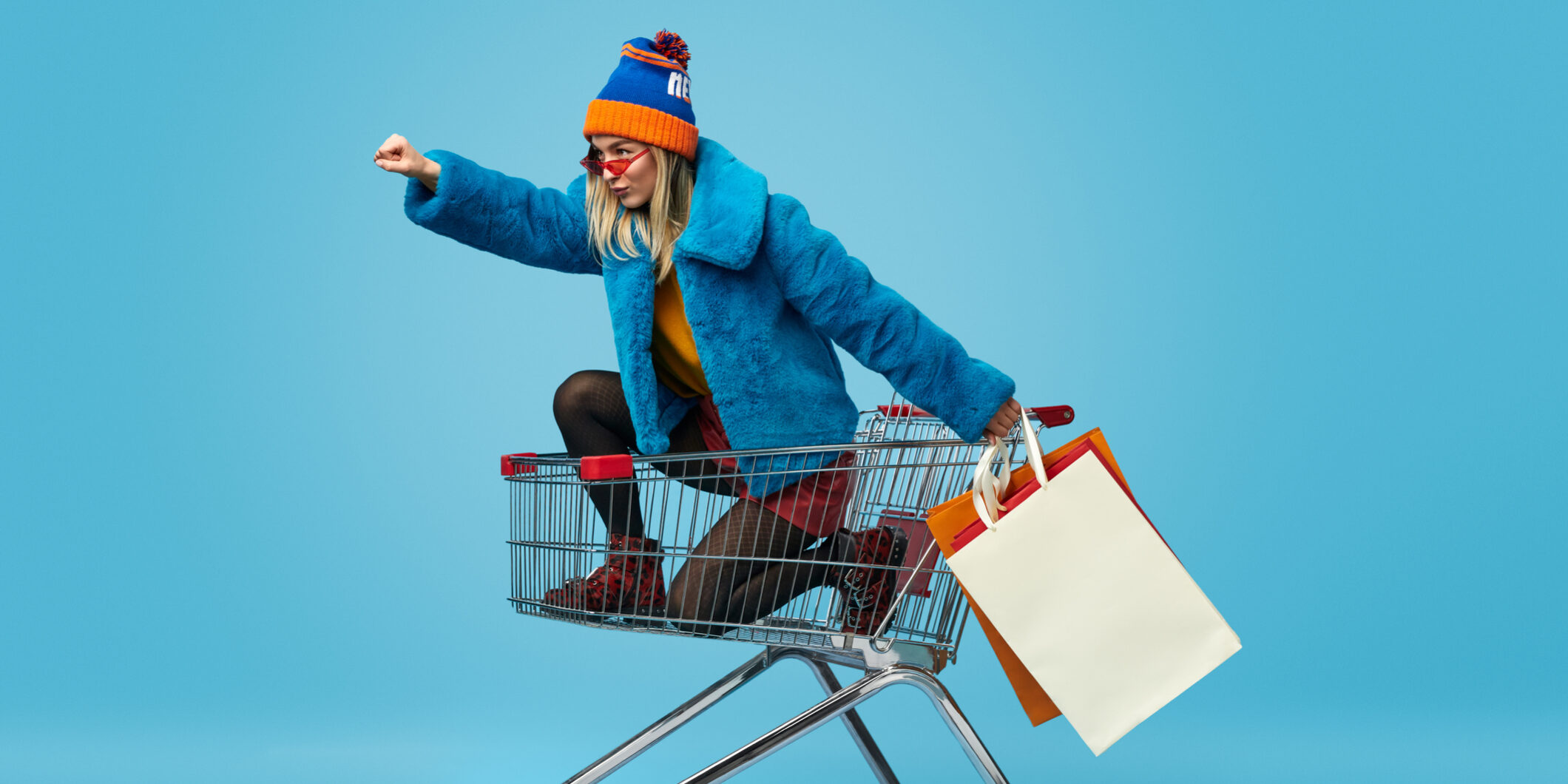 Young woman with shopping bags riding trolley
